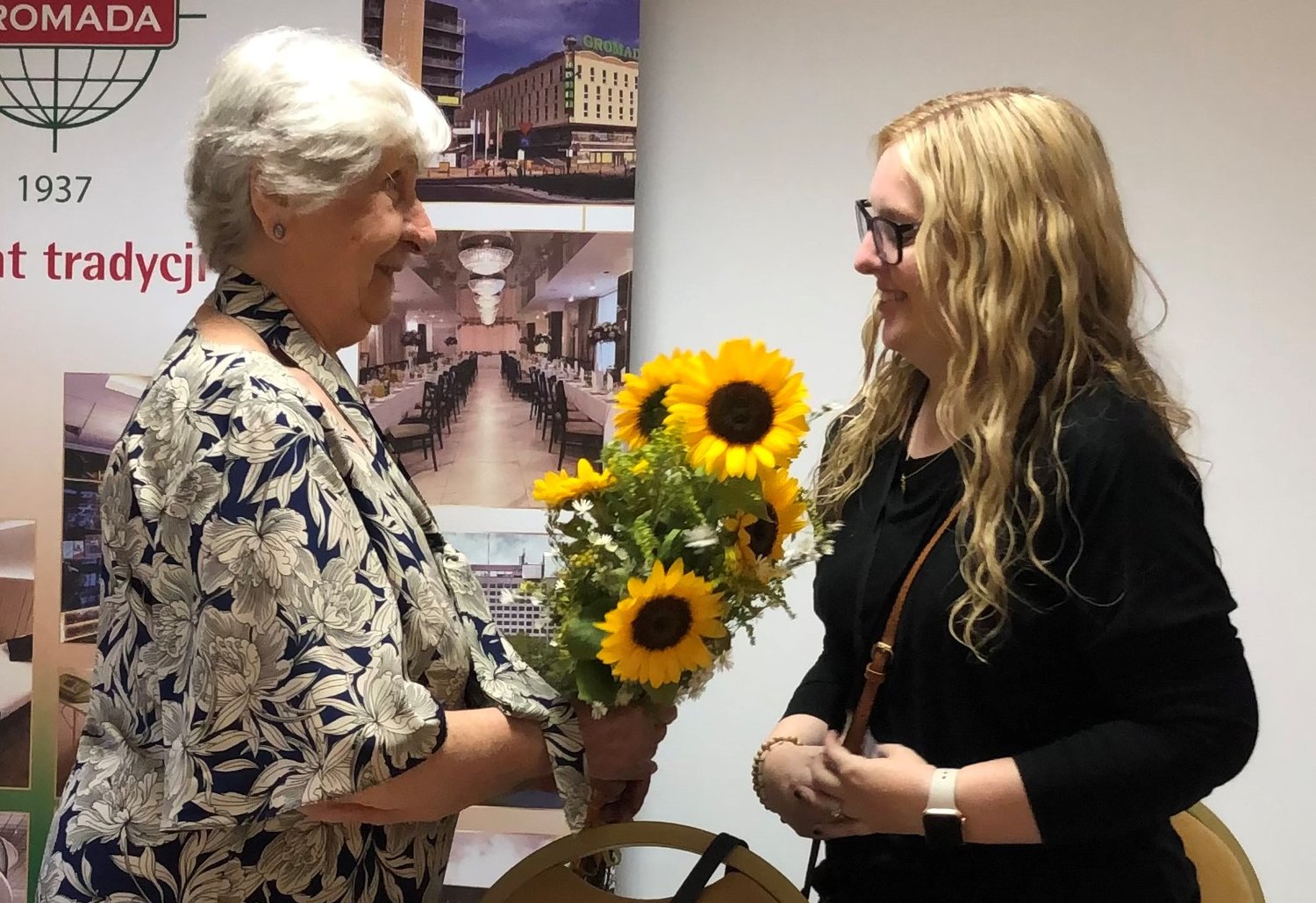 Helias Catholic High School teacher Sarah Kempker, right, presents flowers to Janina Iwanska, a Polish survivor of the Warsaw Uprising and Auschwitz, after Ms. Iwańska shared her story with the members of the Auschwitz-Birkenau Memorial and Museum's International Summer Academy in Poland.